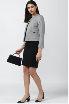 Woman in a gray blazer, black skirt, holding a handbag, and wearing black heels, against a white background.