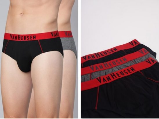 A person wearing black briefs and various colored briefs laid out.