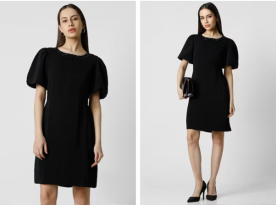 A person modeling a black dress with puff sleeves and accessorizing with a clutch and heels.