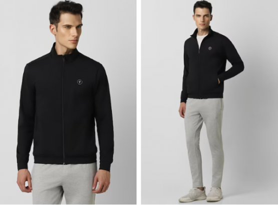 A man in a black zip-up jacket, light grey sweatpants, and white shoes.