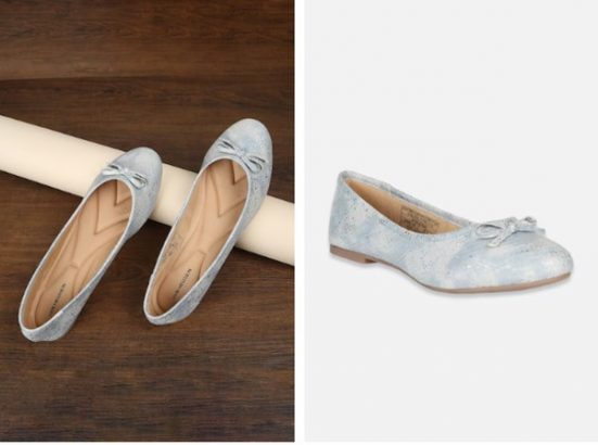 A pair of sparkly silver ballet flats displayed on a wooden floor, one shoe angled towards us.