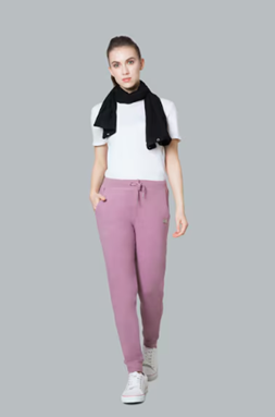 Person wearing a white t-shirt, pink sweatpants, a black sweater over shoulders, and white sneakers.