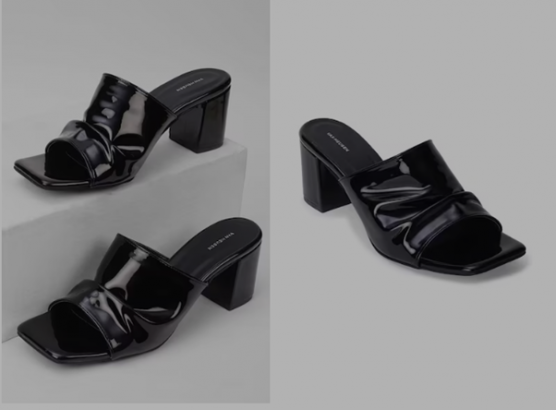 A pair of black patent leather heeled mules on a grey background.