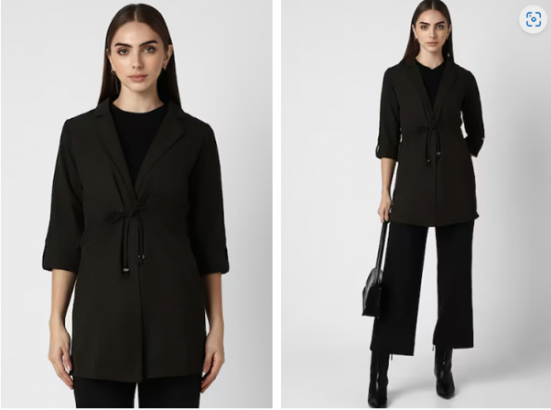 Woman in black blazer and trousers with a handbag and boots.