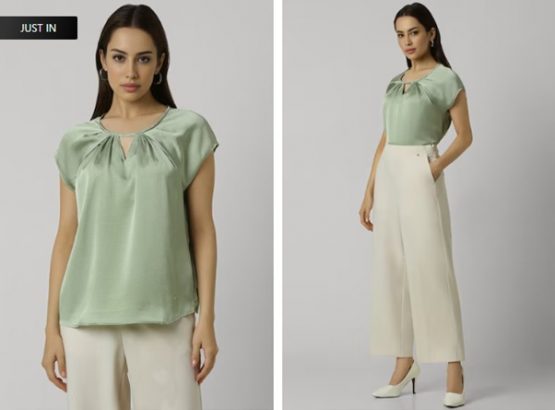 Woman modeling a green blouse and beige culottes with white heels.