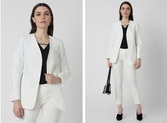 Woman in a white blazer and pants with a black top, paired with heels and a handbag.